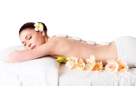 Adult beautiful woman relaxing in spa salon with hot stones on back